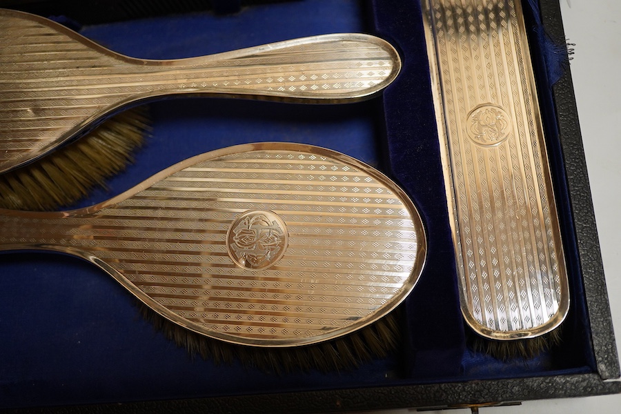 A George V silver six piece engine turned dressing table set Birmingham, 1922 Carringon & Co, comprising hand mirror, pair hairbrushes, pair clothes brushes and a mounted tortoiseshell comb, initialled, in a fitted case